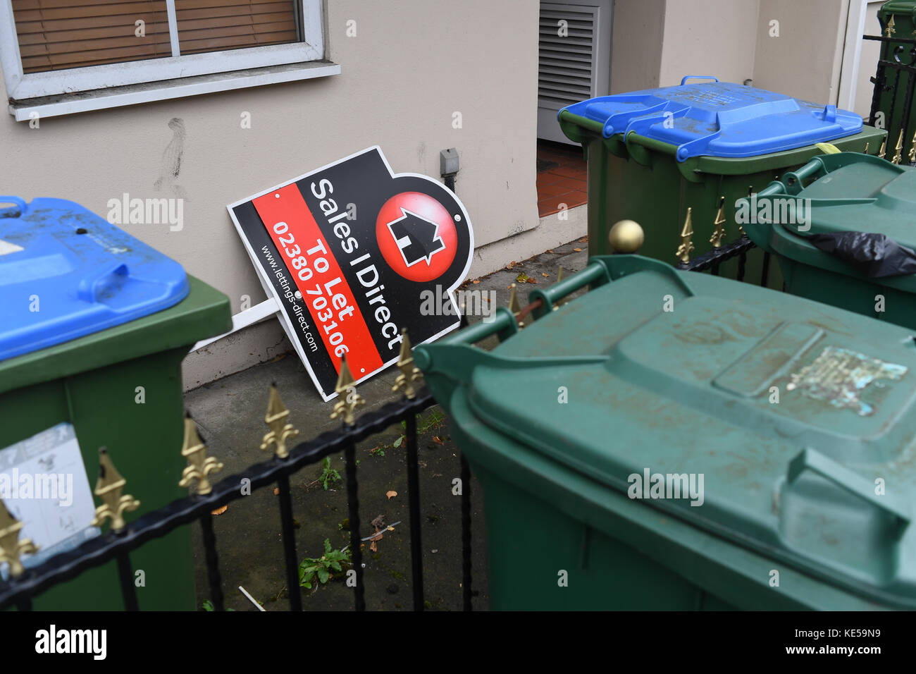 Sales direct To let sign dumped behind bins outside house. Stock Photo