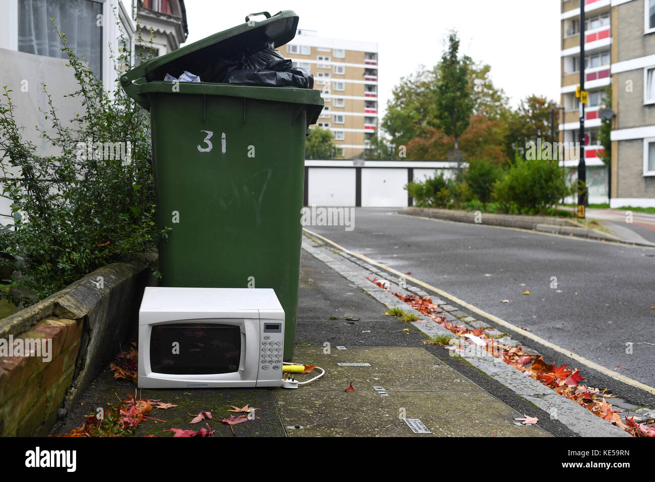 A white microwave is put out with the bins for recycling Stock Photo
