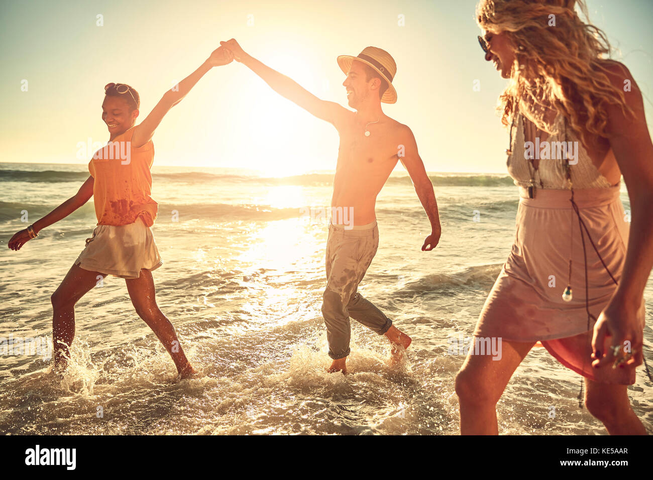 Playful young friends splashing in sunny summer ocean surf Stock Photo