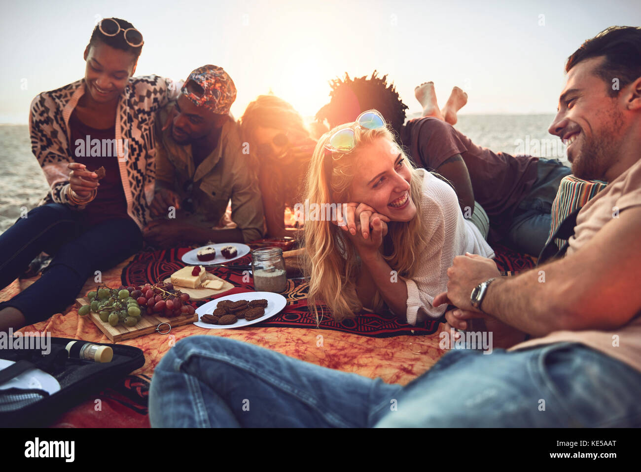 Young friends hanging out, enjoying picnic on sunny summer beach Stock Photo