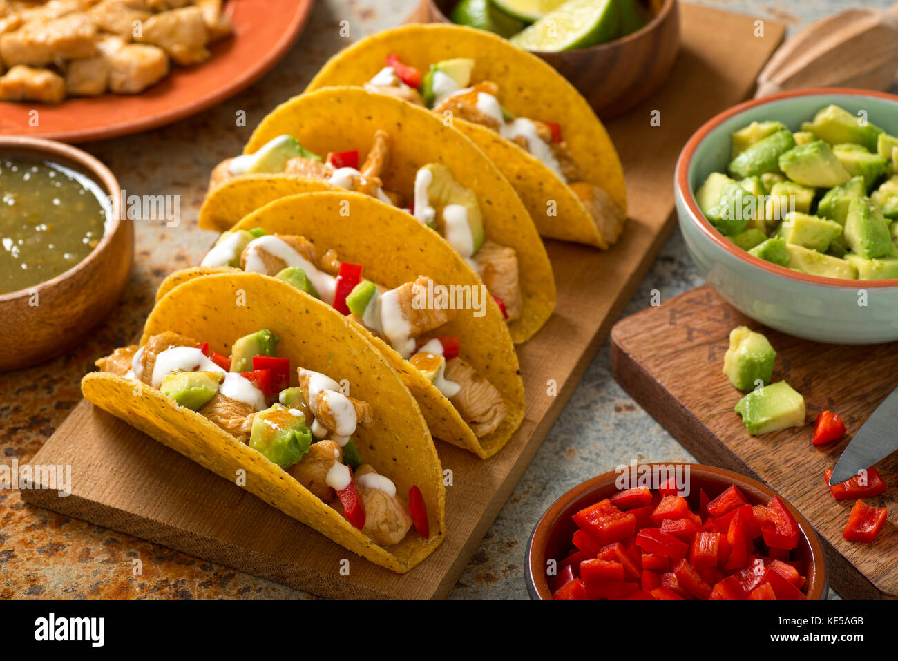 Delicious homemade chicken tacos salsa verde with avocado, red pepper, sour cream and lime. Stock Photo