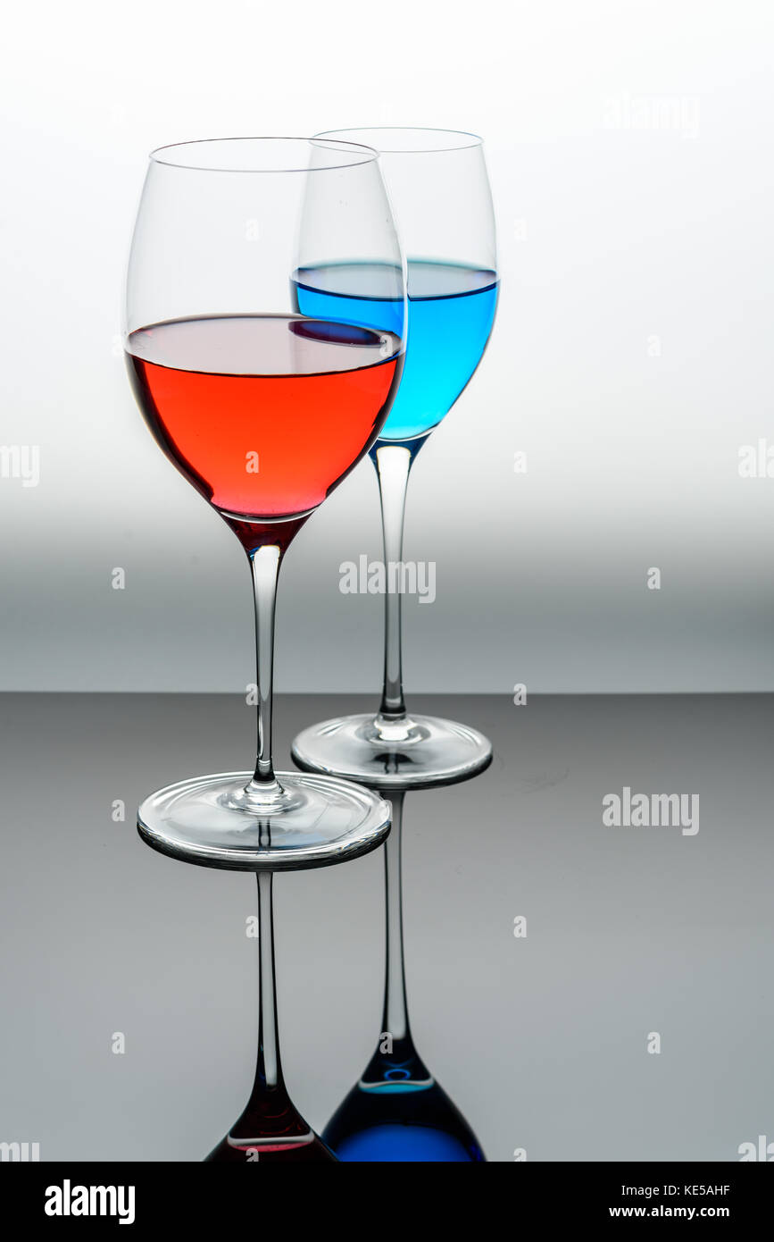 two glasses with blue colored water and red wine Stock Photo