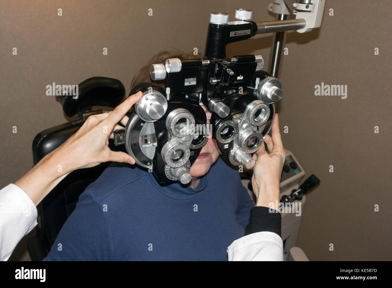 Ophthalmologist tests patient's eyes for individual lenses with a Phoropter. Minneapolis Minnesota MN USA Stock Photo