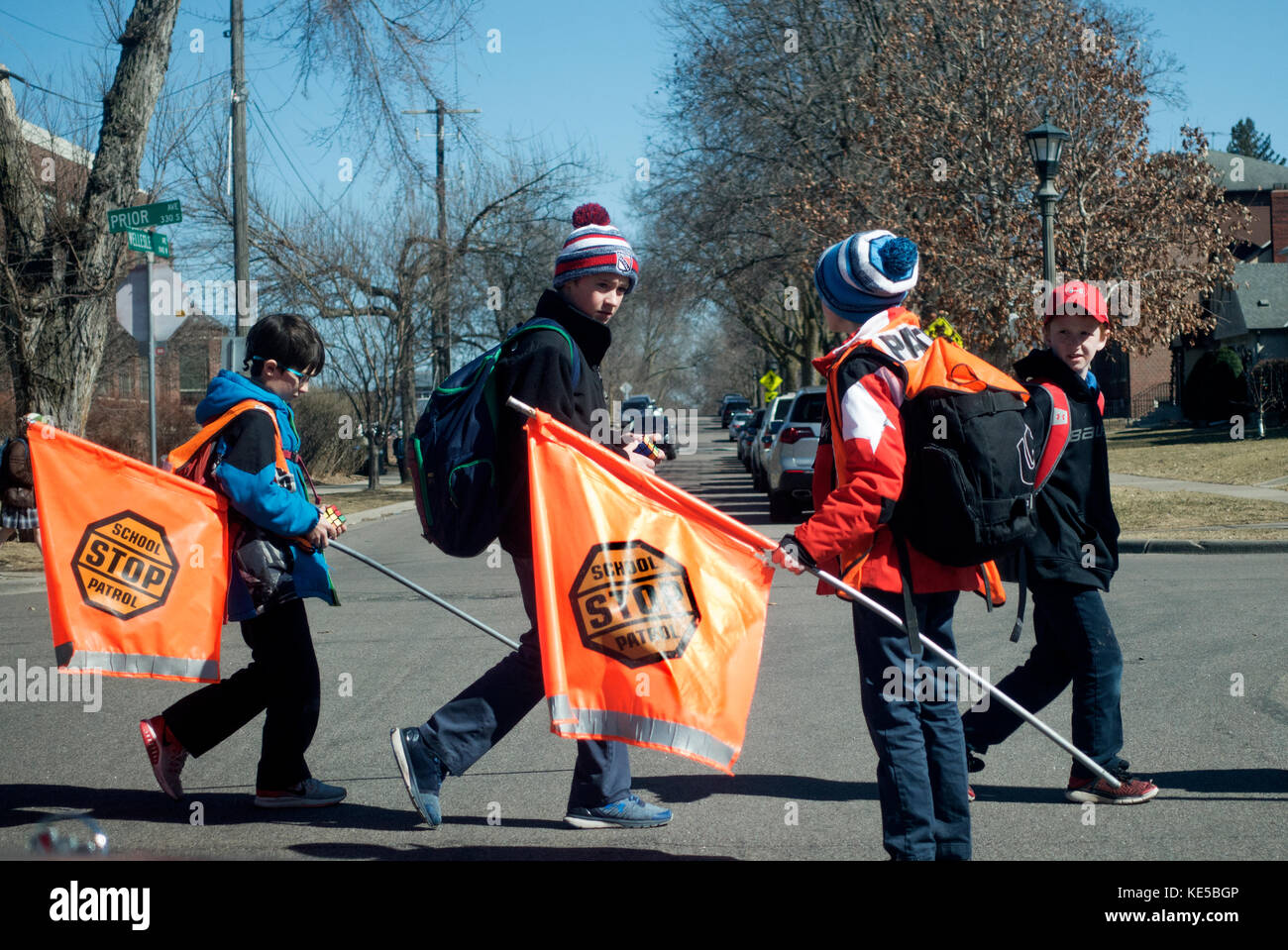 School patrol guiding students safely across the street with orange stop sign flags. St Paul Minnesota MN USA Stock Photo