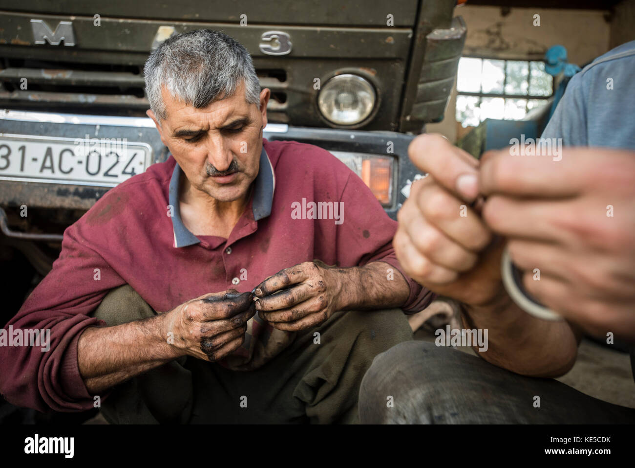 Garage of the Nikitin Kolkhoz at Ivanovka village, Azerbaijan. Workers prepare trucks for grape harvesting. These vehicles deliver grape to Ganja wine factory. Ivanovka is a village with mainly Russian population which maintained the last kolkhoz in Azerbaijan. Stock Photo