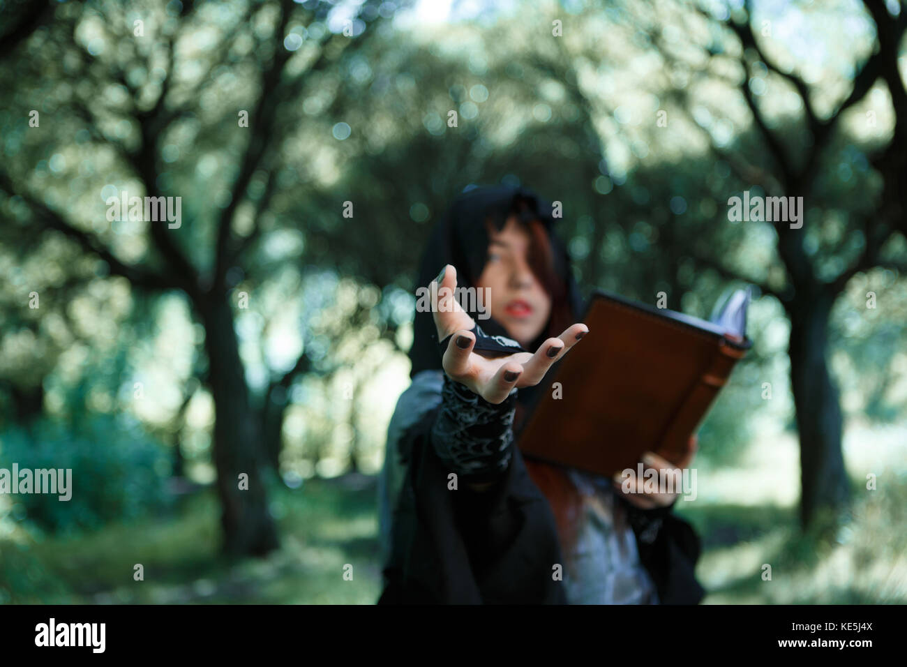 Image of witch with outstretched hand and book, focus on hand,in dark ...