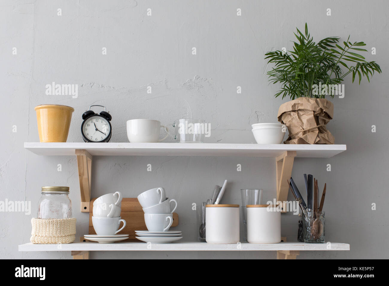 Utensils and mugs on shelf gray wall Stock Photo