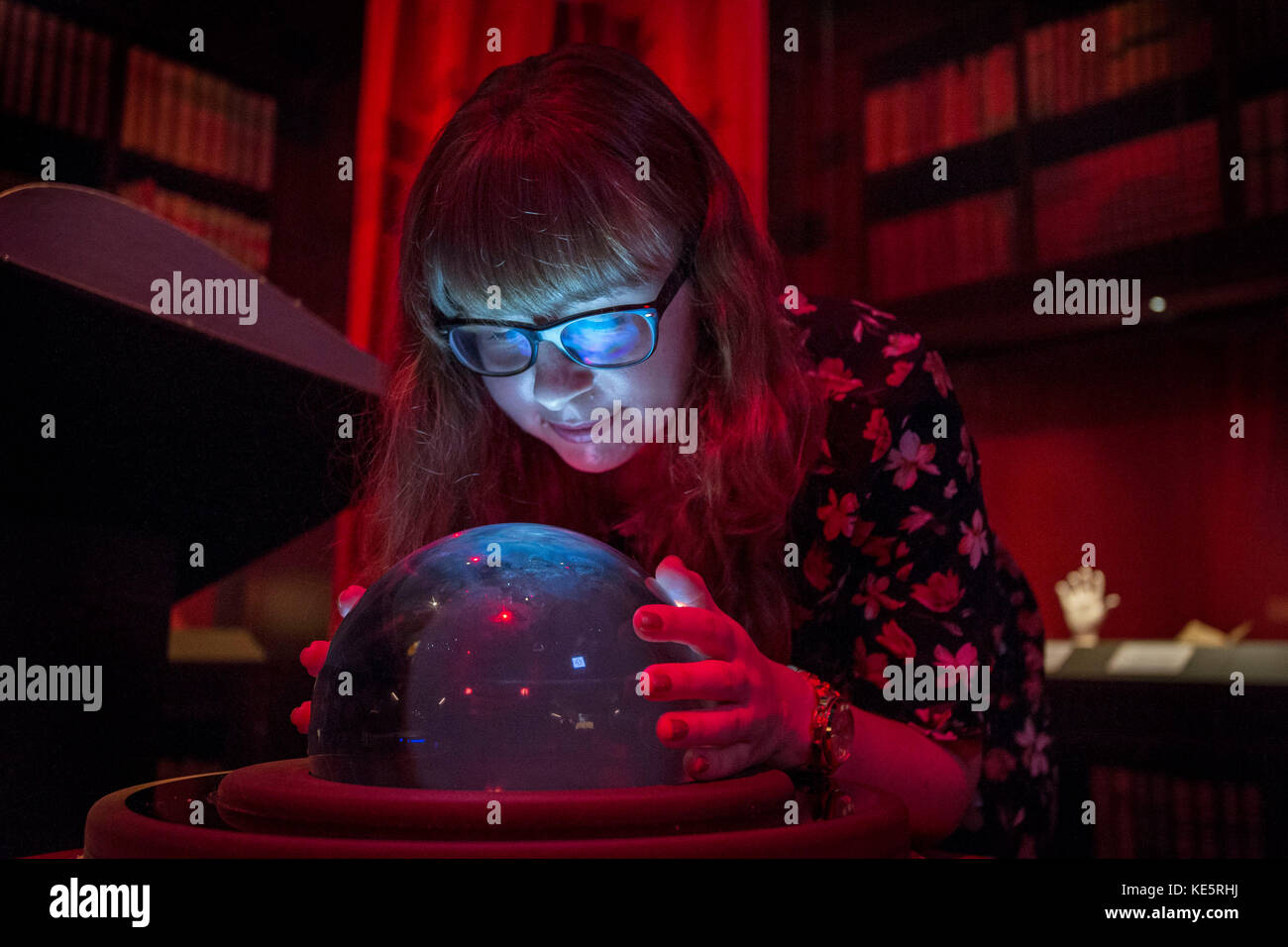 A visitor looks at a crystal ball giving a visual representation of divination for visitors during a press preview for the Harry Potter: A History of Magic exhibition at the British Library in London. Stock Photo