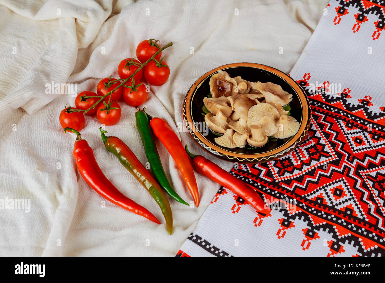 mushrooms on a plate of tomatoes pepper and Ukrainian embroidery mushrooms sauteed in small white bowl Stock Photo