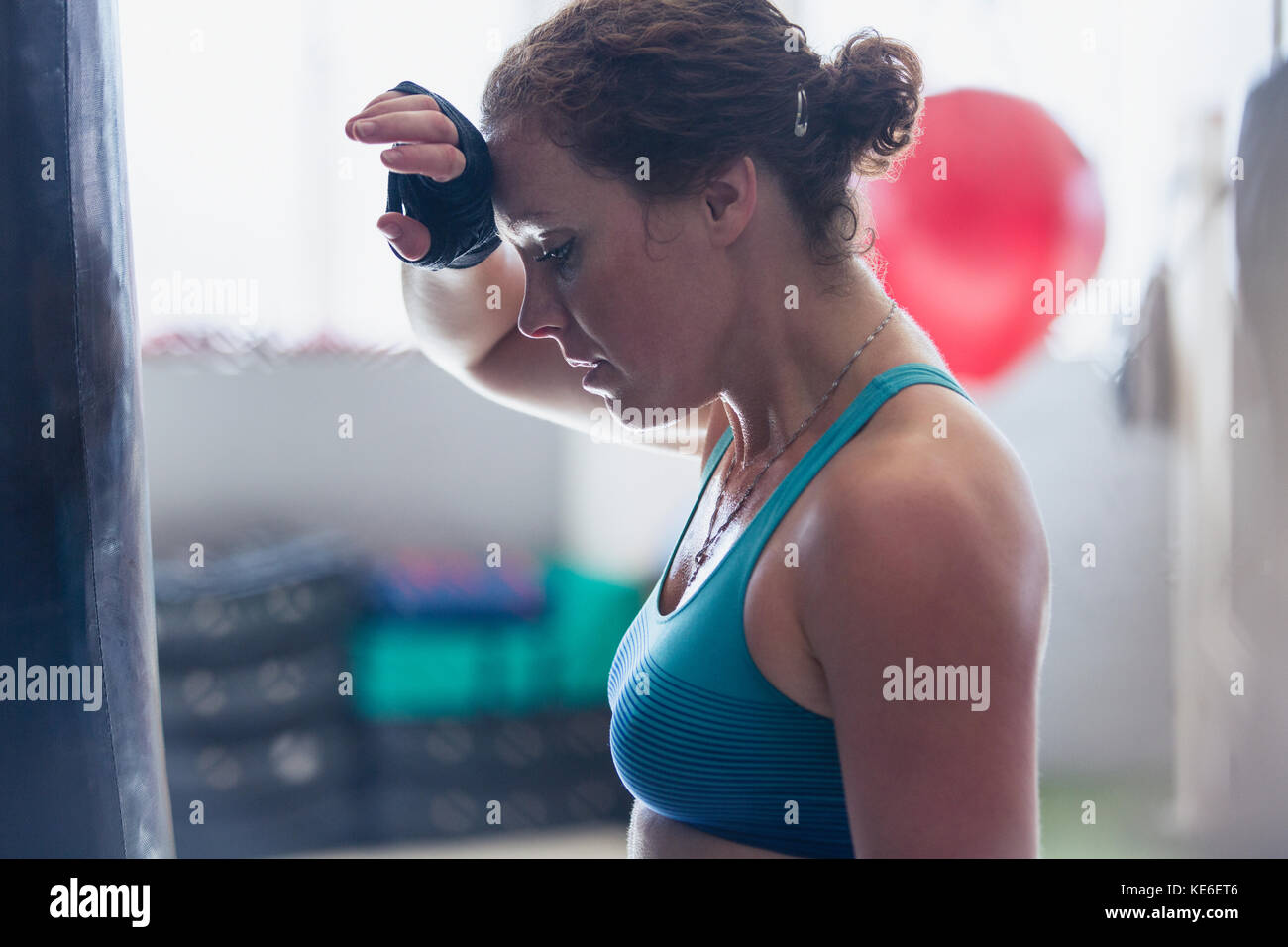 Tired female boxer wiping sweat from brow in gym Stock Photo