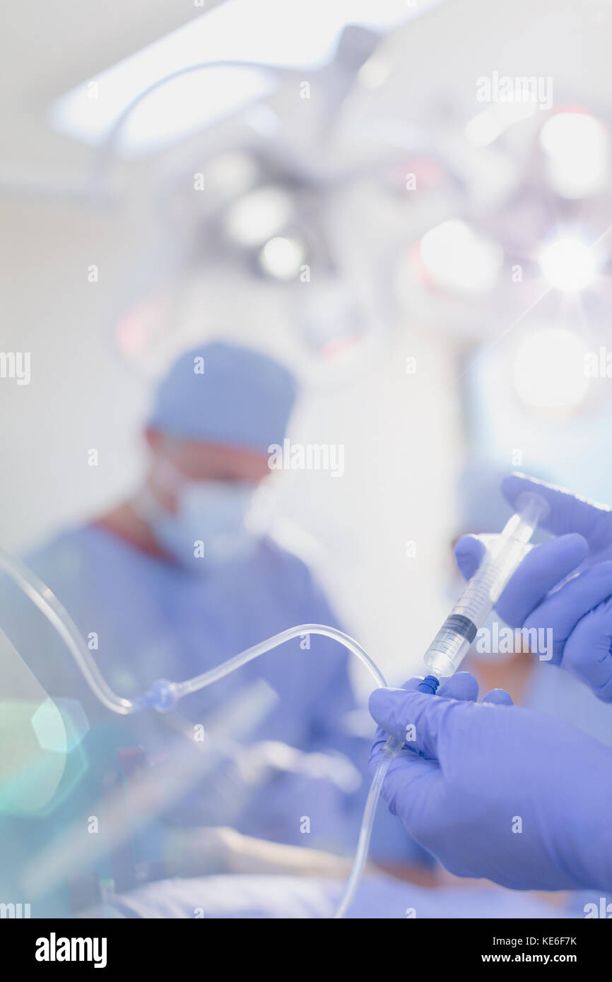 Close up anesthesiologist injecting anesthesia medicine into IV drip in operating room Stock Photo