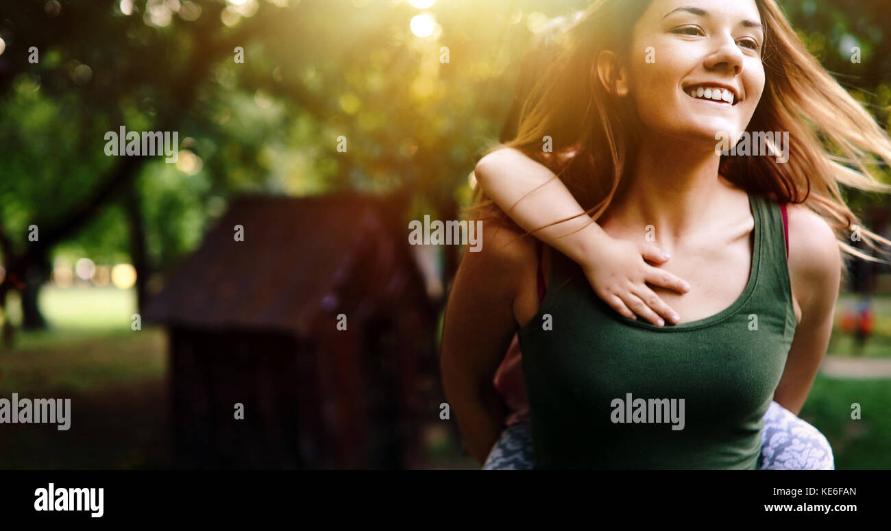 Portrait of young woman carrying little kid on her back Stock Photo