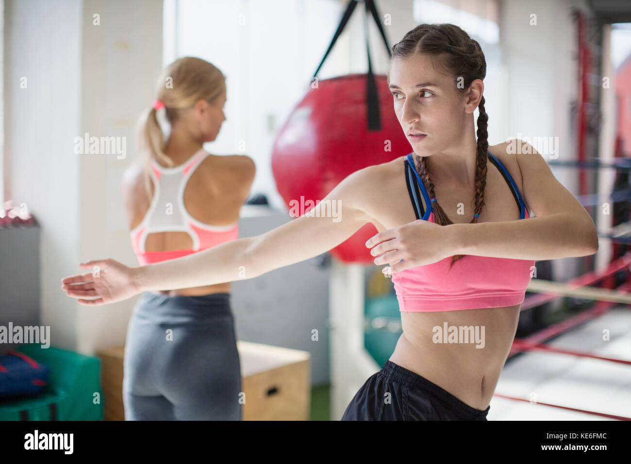 Focused young female boxer stretching, twisting in gym Stock Photo