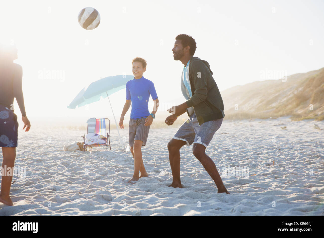 Father and children playing soccer on sunny summer beach Stock Photo