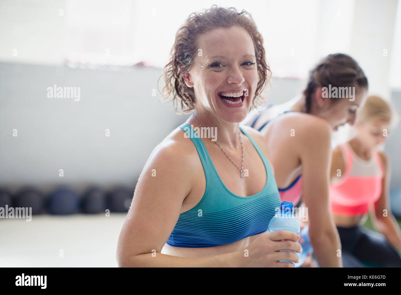 Portrait smiling, laughing woman drinking water and resting post workout at gym Stock Photo