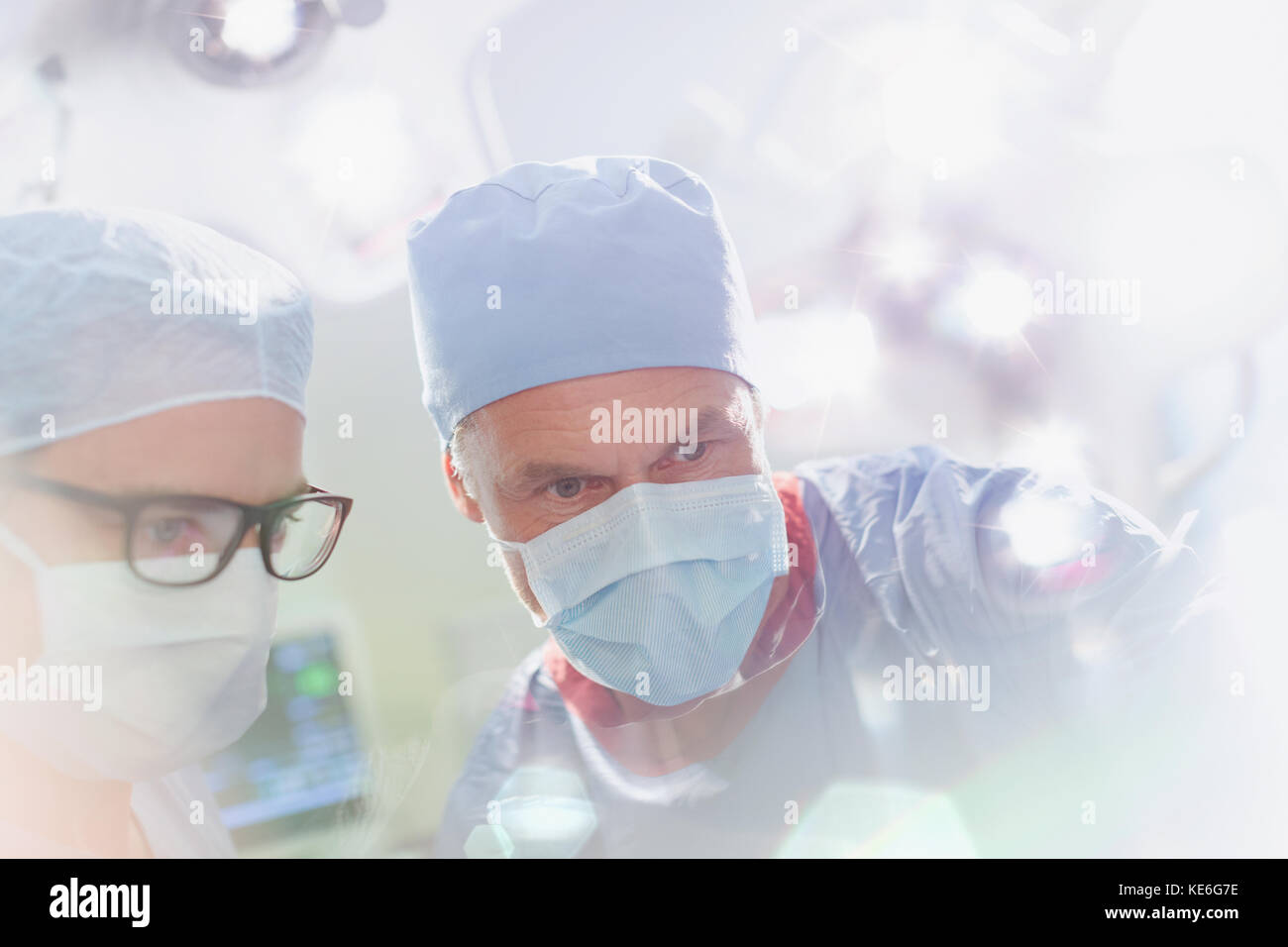 Surgeons wearing surgical mask looking down in operating room Stock Photo