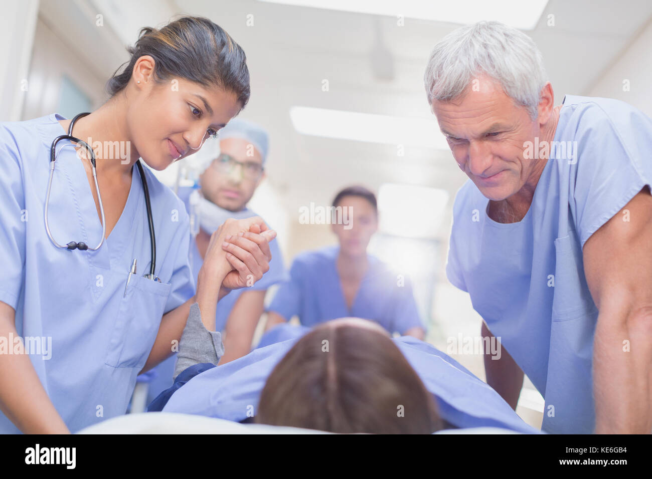 Caring surgeons talking to patient on stretcher in hospital corridor Stock Photo