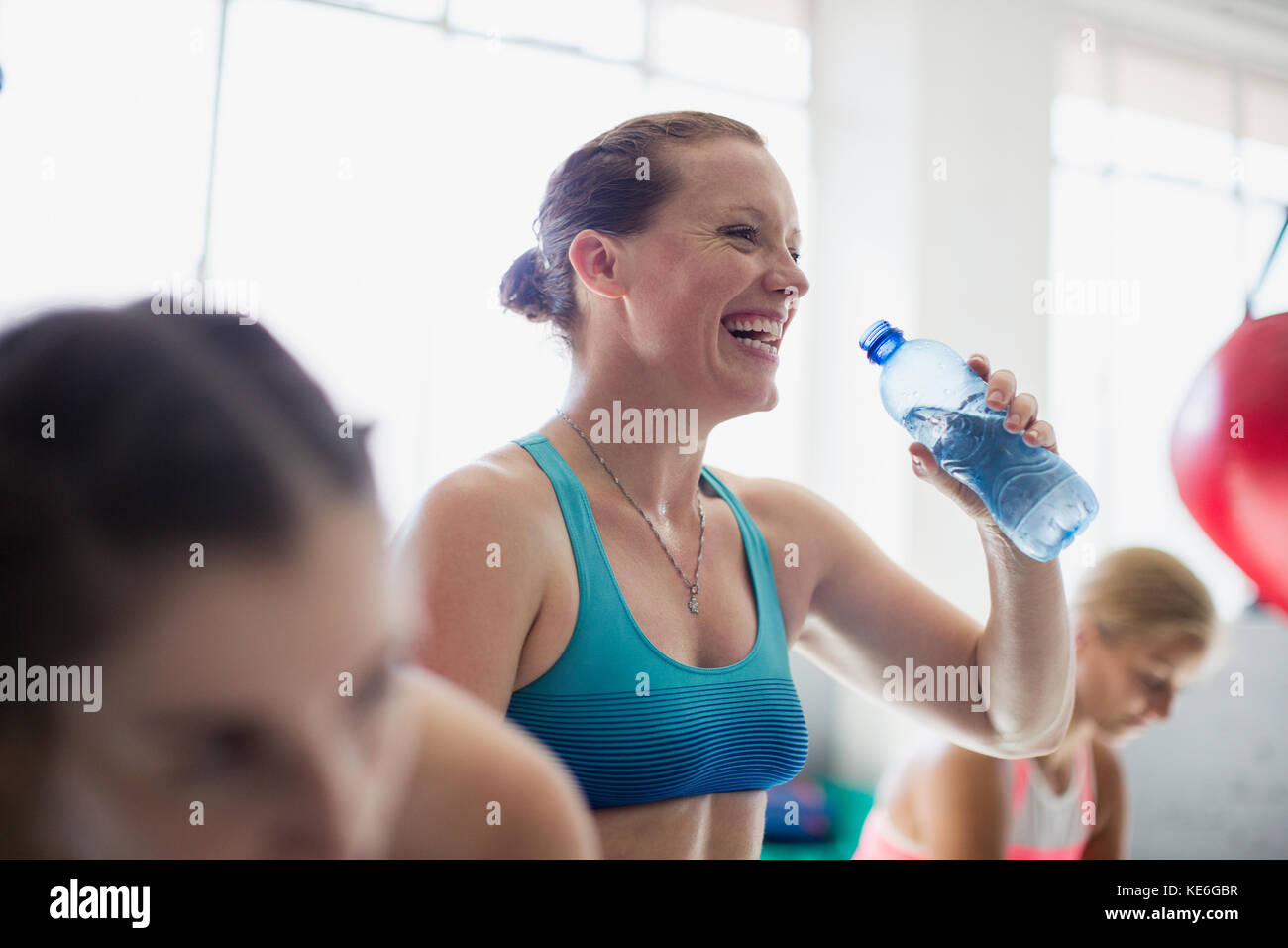 Laughing woman drinking water and resting post workout at gym Stock Photo