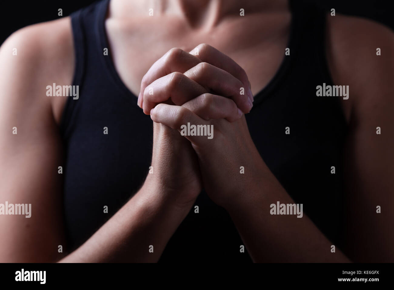 Hands of faithful woman praying, hands folded, interlaced fingers in worship to god / pray prayer folded christian catholic worshiper worshiping Stock Photo