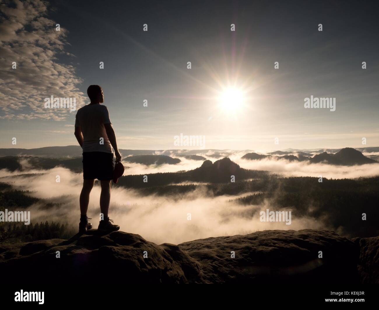 Man at the top of a mountain looking the misty landscape around. Feel ...