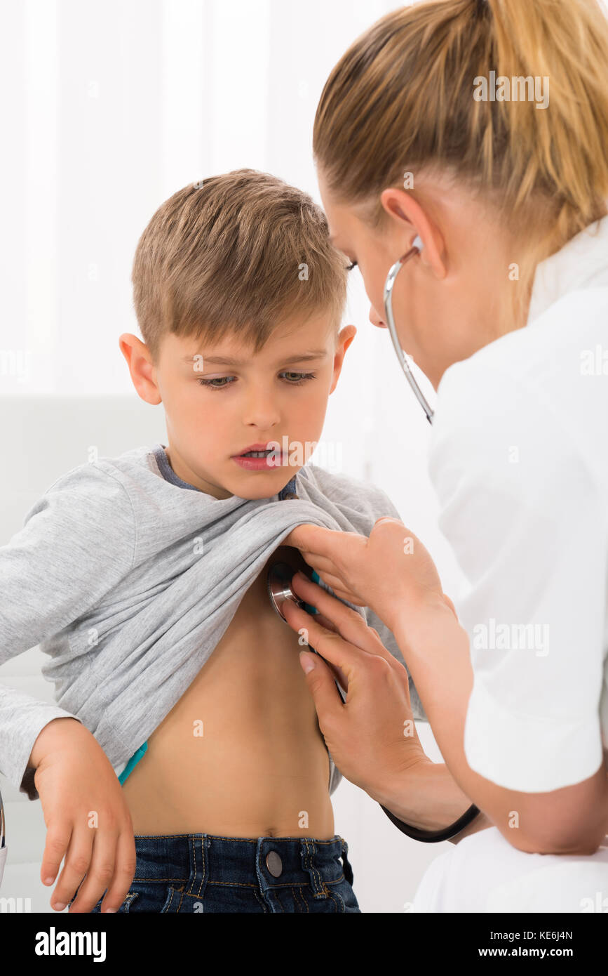 Female Doctor Examining Boy With Stethoscope In Clinic Stock Photo
