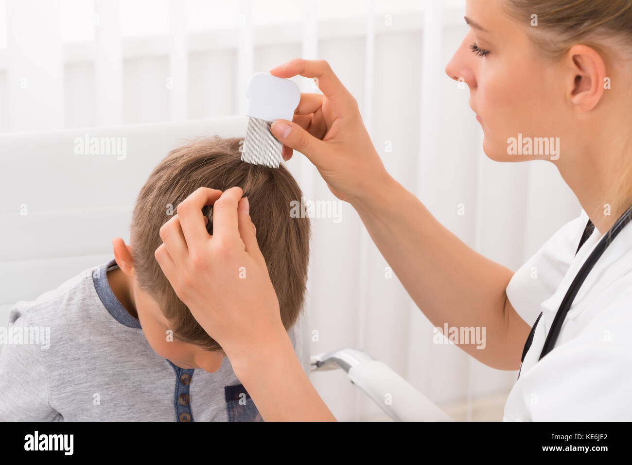 Close-up Of Female Doctor Doing Treatment On Boy's Hair With Comb Stock Photo