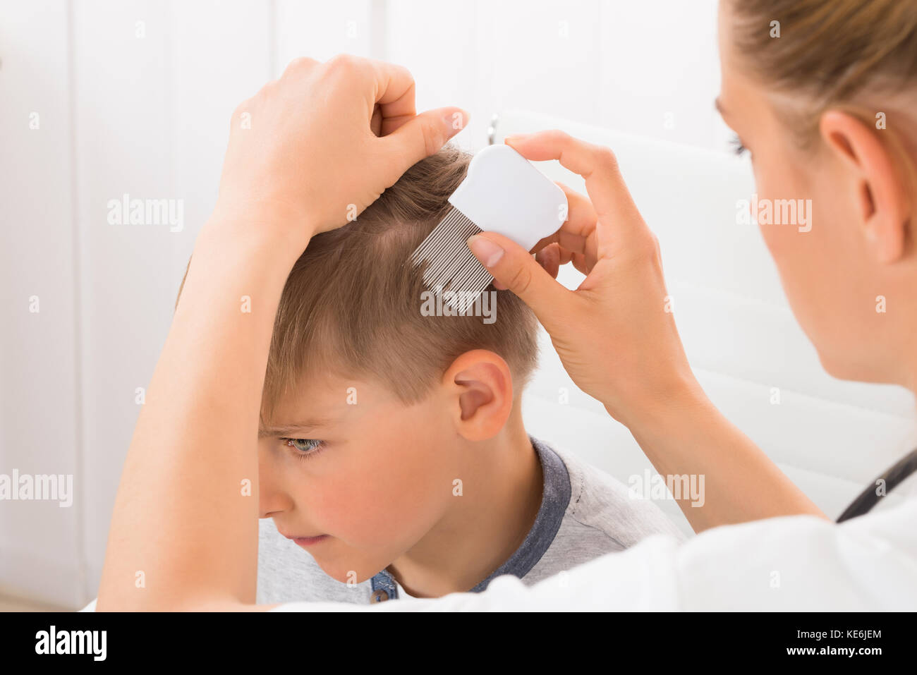 Close-up Of Female Doctor Doing Treatment On Boy's Hair With Comb Stock Photo