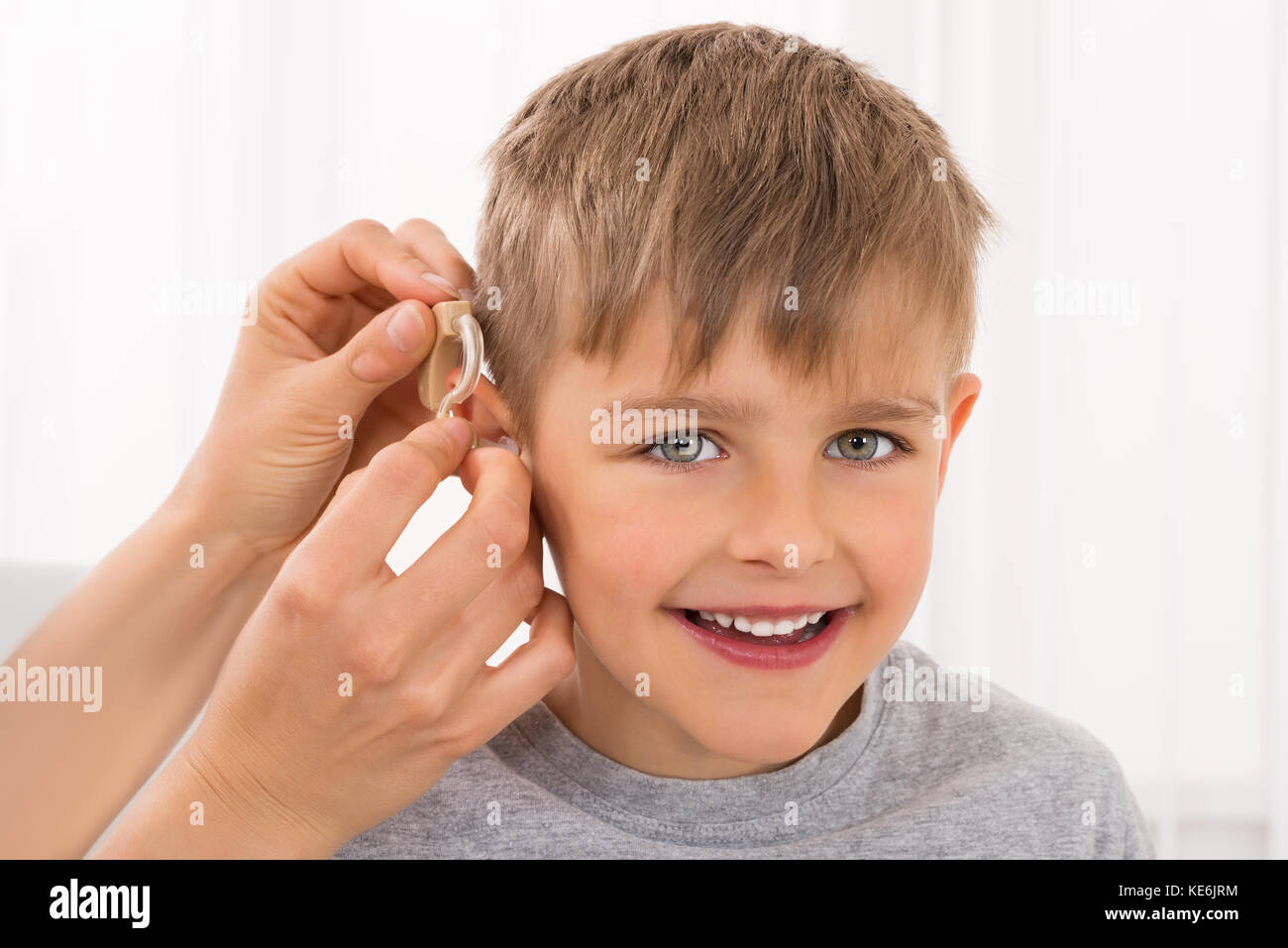 Closeup Of A Doctor Fitting Hearing Aid On Smiling Boy's Ear Stock Photo Alamy