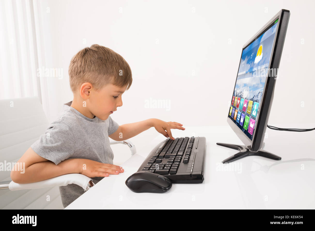 Little Boy Typing On Keyboard At Home Stock Photo