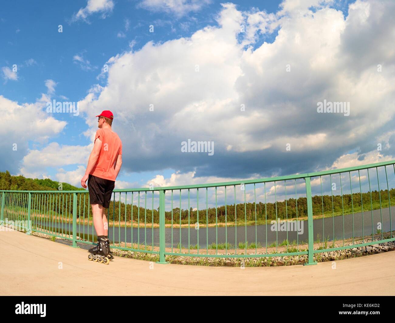Rear view to inline skater in red tshirt and black pants skating on