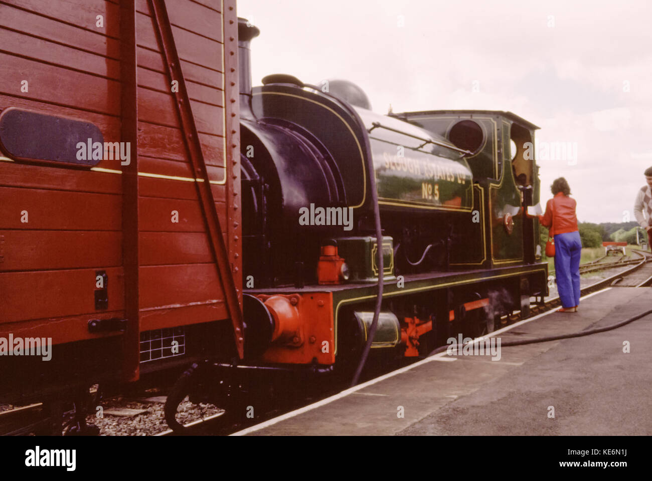 Steam locomotive train at station platform with woman talking to the train driver. Steam train is called Slough Estates no 5, Embsay and Bolton Abbey Steam Railway, Yorkshire, England, UK in the 1980s Stock Photo