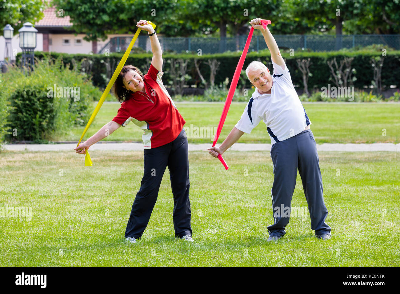 Happy Senior Couple Exercising With Yoga Belt In Park Stock Photo
