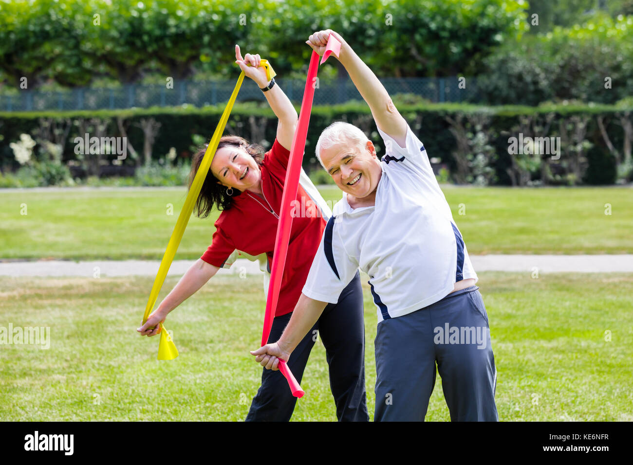 Happy Senior Couple Exercising With Yoga Belt In Park Stock Photo