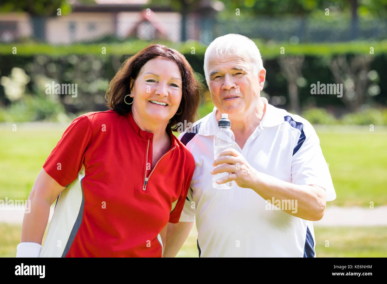 Portrait Of Senior Couple Standing In Park Holding Bottle Of Water Stock Photo