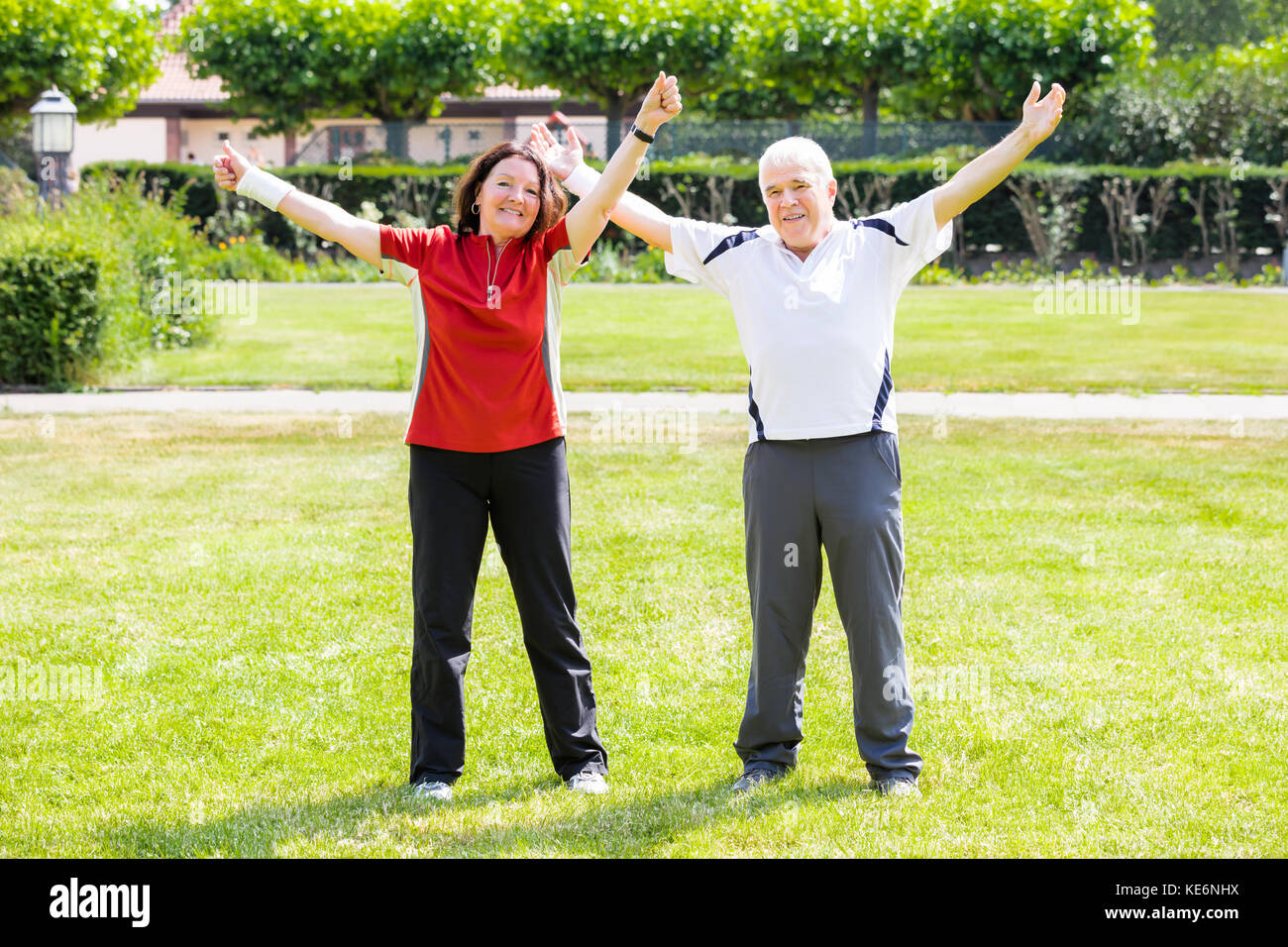 Elderly Senior Couple Raising Arms In Park At Morning Stock Photo