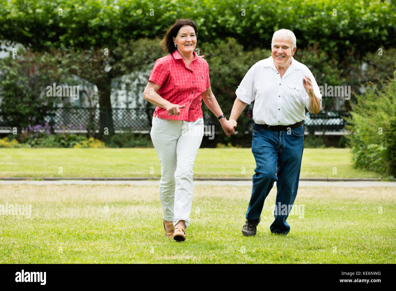 Happy Senior Couple Running In Park Holding Hands Stock Photo - Alamy