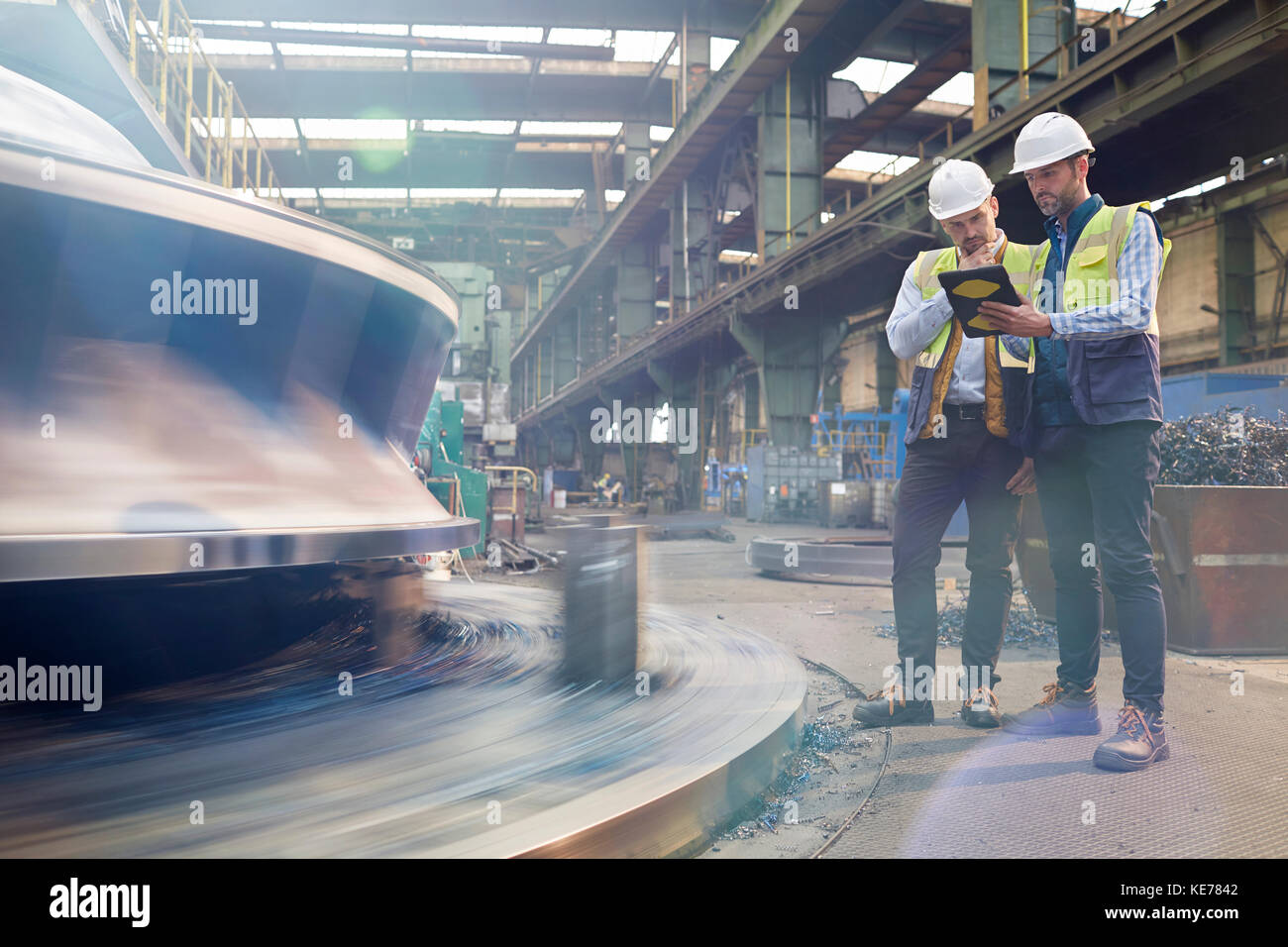 Male foreman and engineer with digital tablet talking in factory Stock Photo