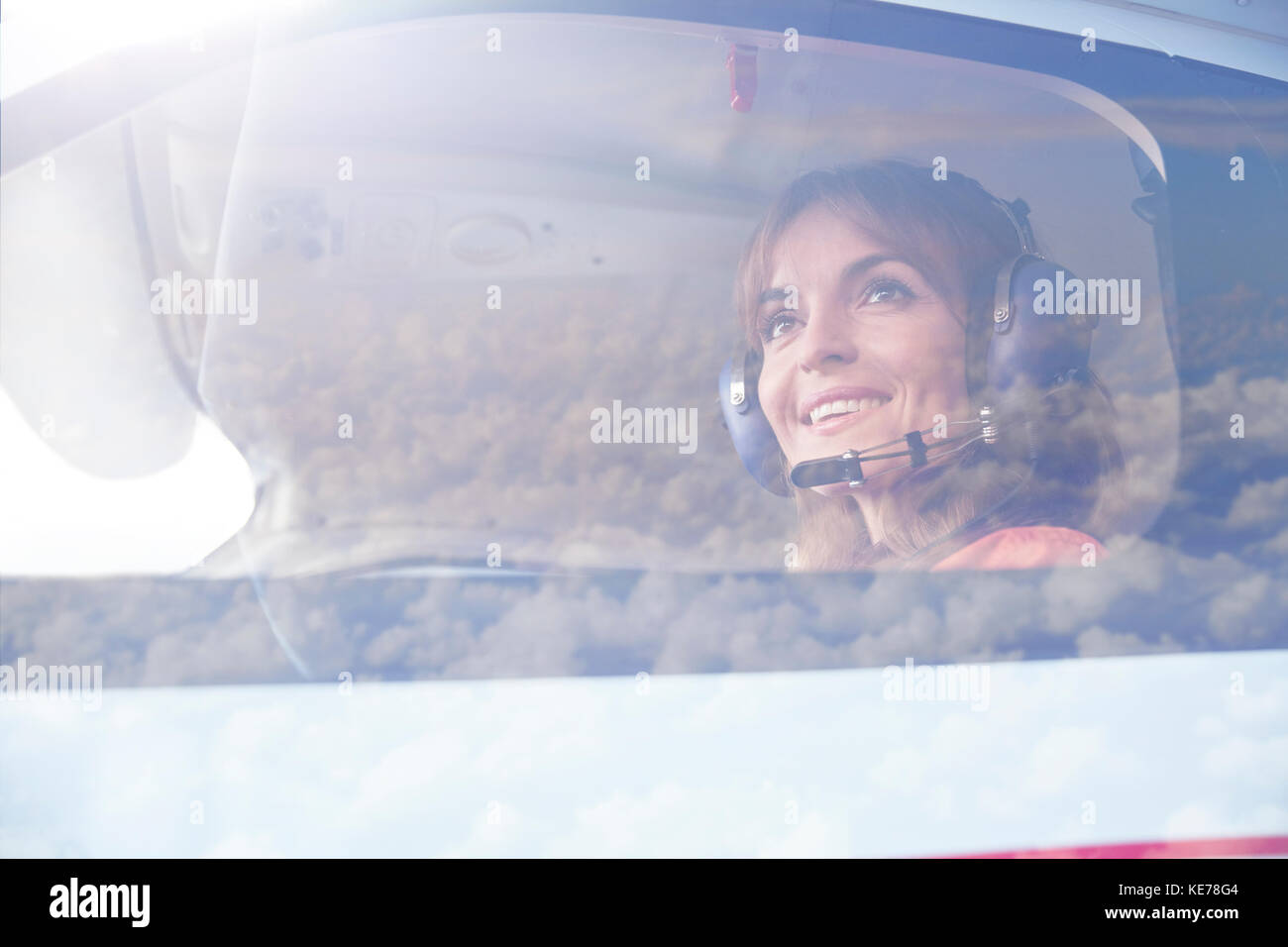 Smiling female pilot flying airplane in cockpit Stock Photo