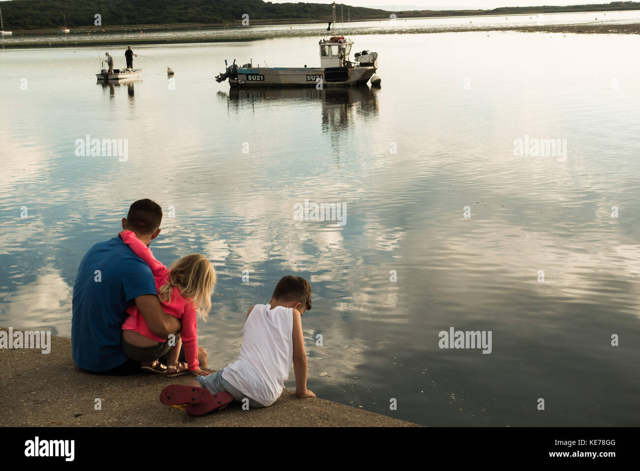 A calm summer evening at Christchurch Harbour, Hampshire, England with father and his two children Stock Photo
