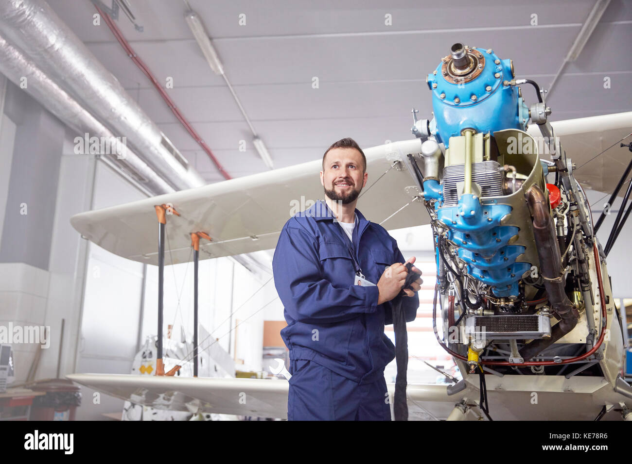 Portrait confident male airplane mechanic working on biplane in hangar Stock Photo