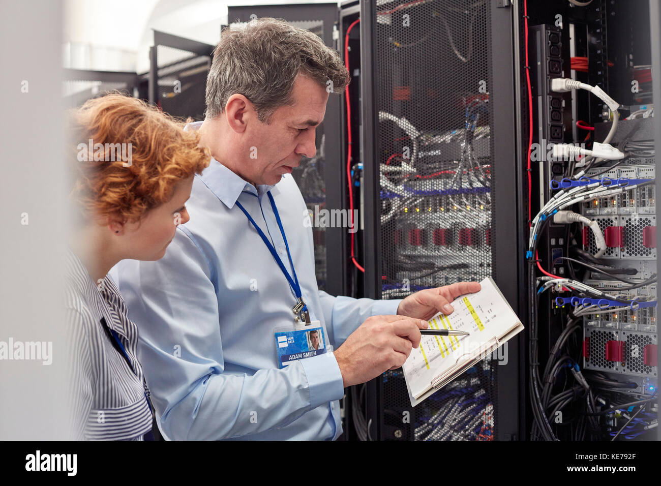 IT technicians with clipboard examining panel in server room Stock Photo