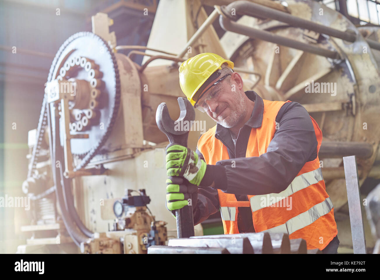 Male worker using large wrench on machinery in factory Stock Photo