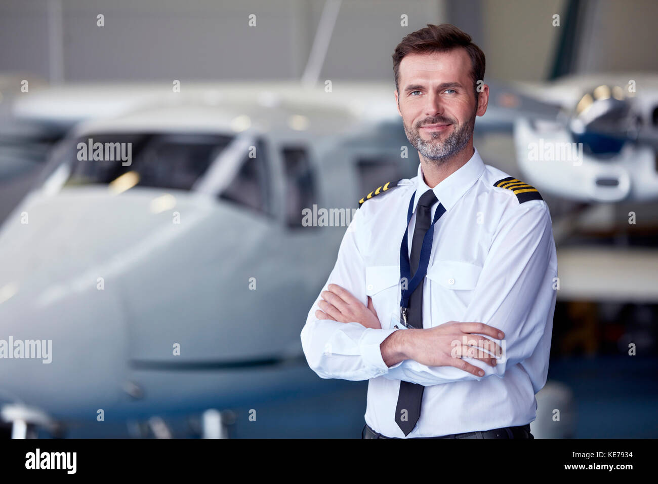 Portrait confident male pilot standing near airplane in hangar Stock ...