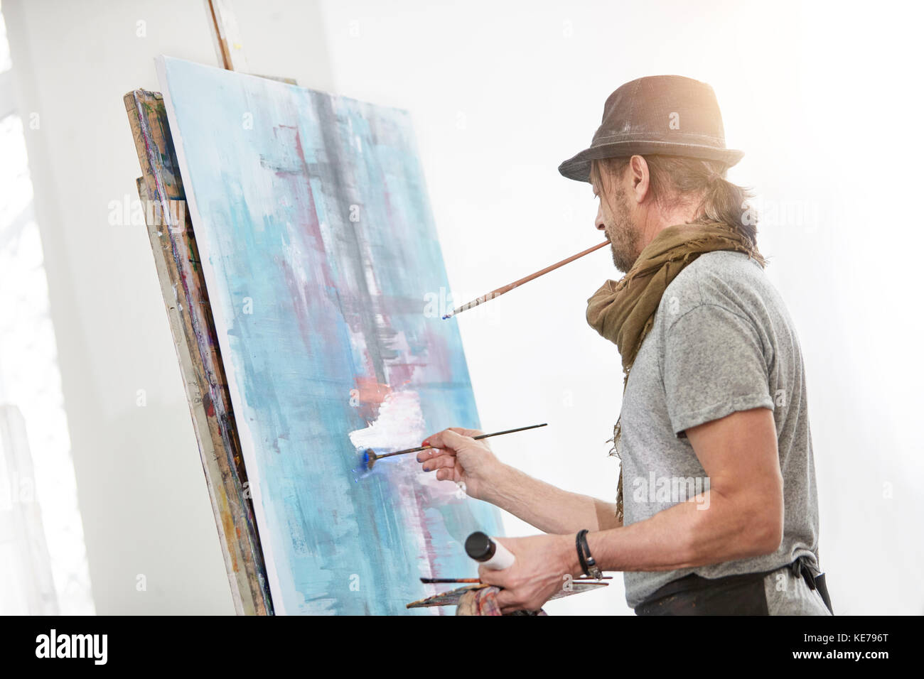Male artist painting at easel in art studio Stock Photo