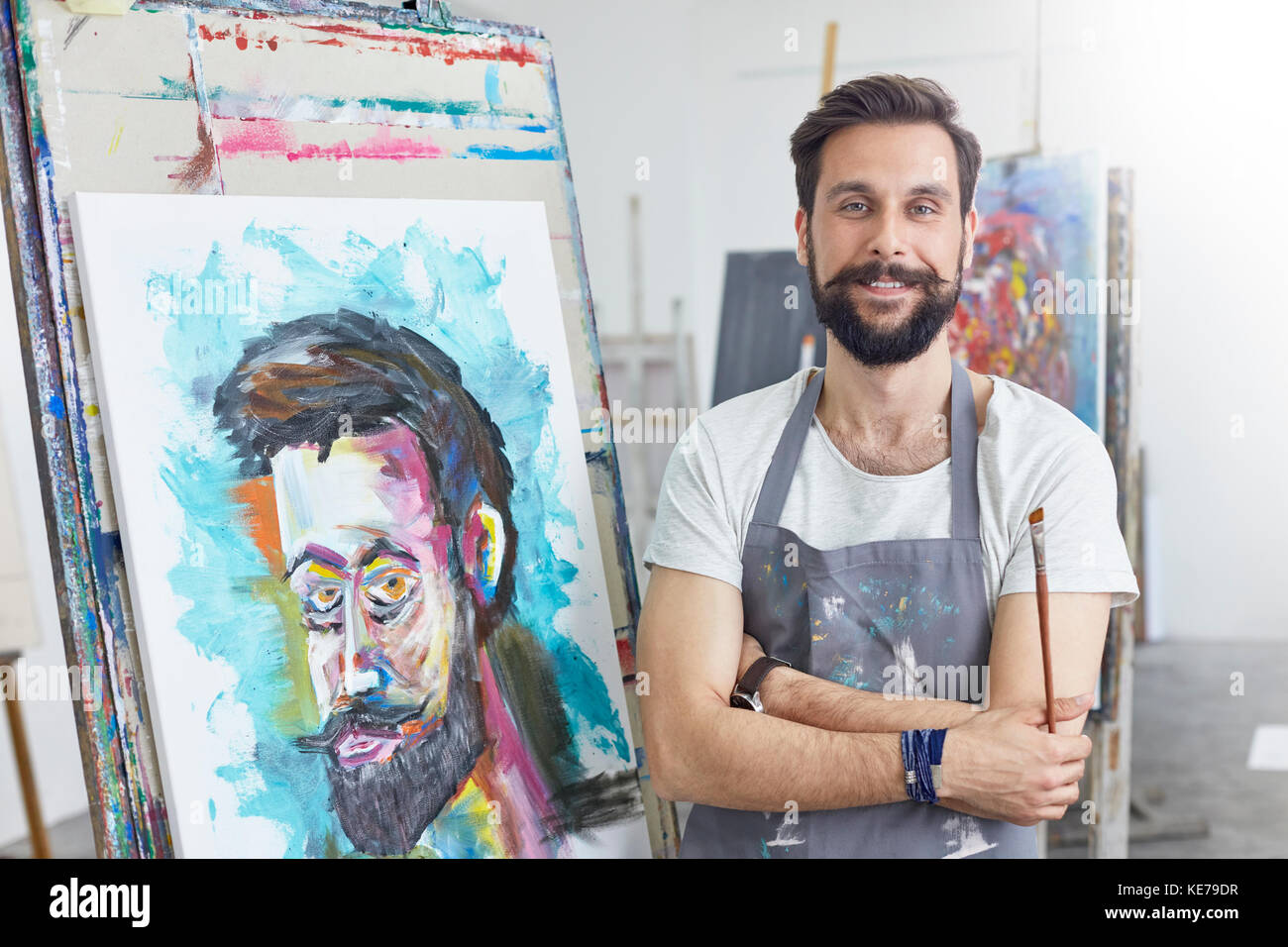 Portrait smiling, confident male artist painting in art studio Stock Photo