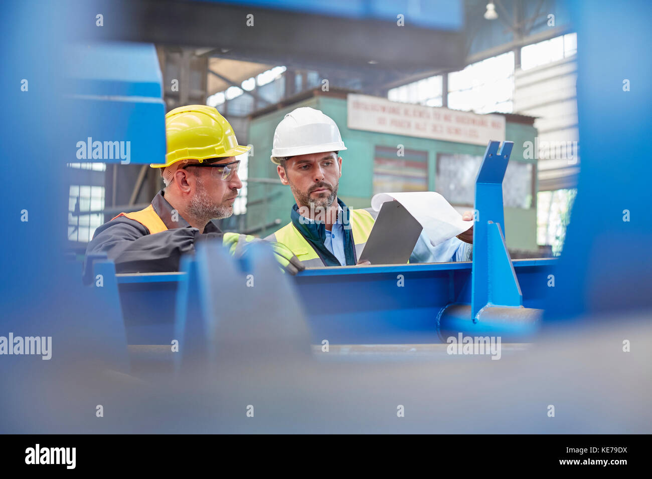 Male foreman and worker reviewing paperwork in factory Stock Photo