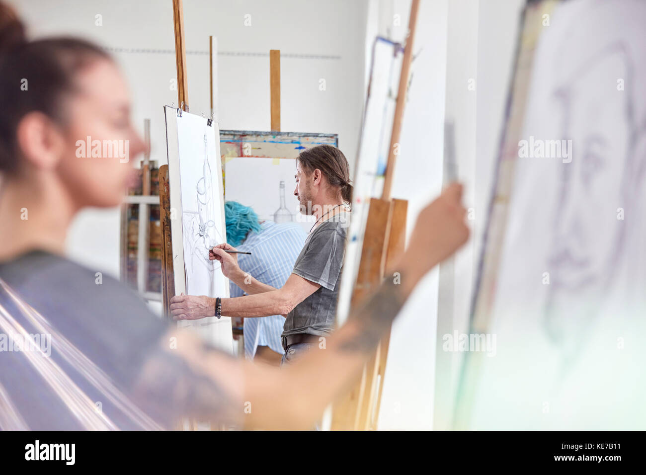 Artists sketching at easels in art class studio Stock Photo