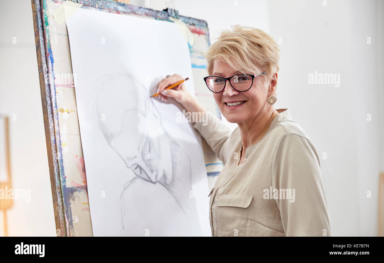 Portrait smiling female artist sketching at easel in art studio Stock Photo