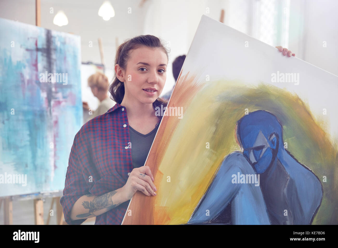 Portrait female artist holding, showing painting in art class studio Stock Photo