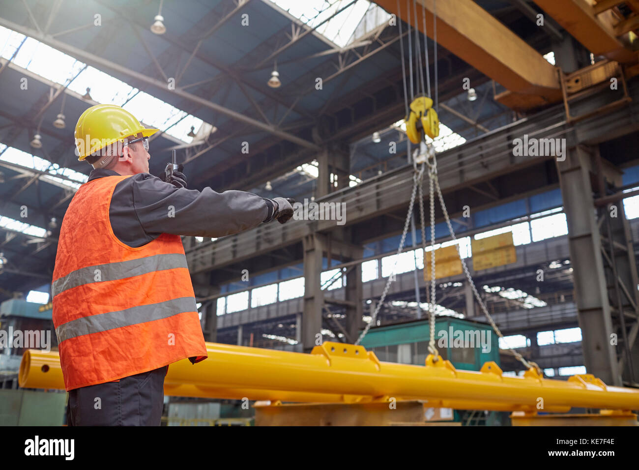 Male worker guiding hydraulic crane in factory Stock Photo